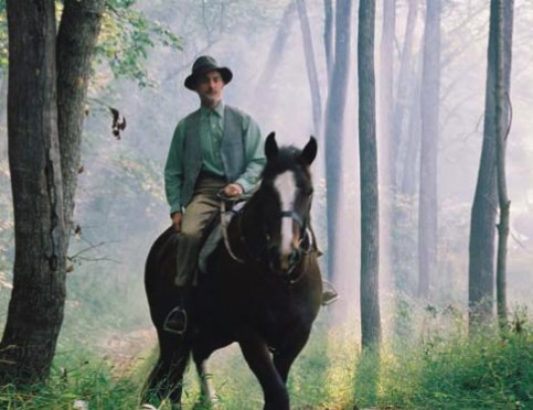 Nate riding a horse through the woods